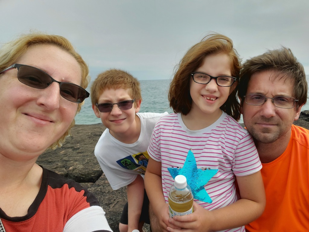 Woman, two children and a man on a beach in front of a lake
