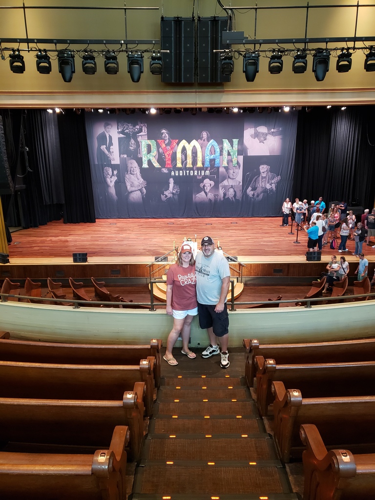 Couple standing in balcony of theater with words "Ryman Auditorium" in the background