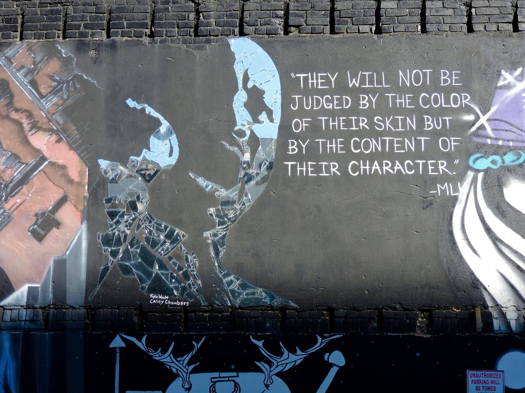 Image of graffiti on a wall with text "they will not be judged by the color of their skin, but by the content of their character"