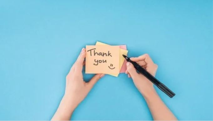 Blue background with Thank you written on a yellow post it note