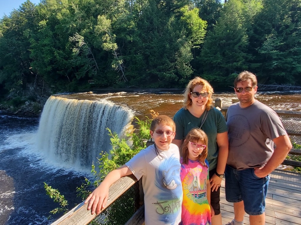 two adults and two children in front of a waterfall