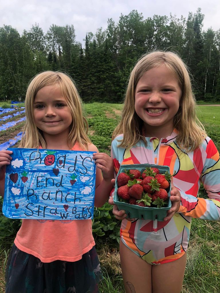 Two young ladies showing artwork and strawberries