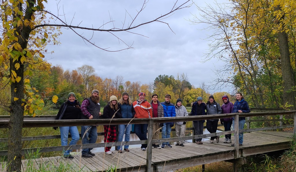 A group of people standing on a wooden bridge in a line
