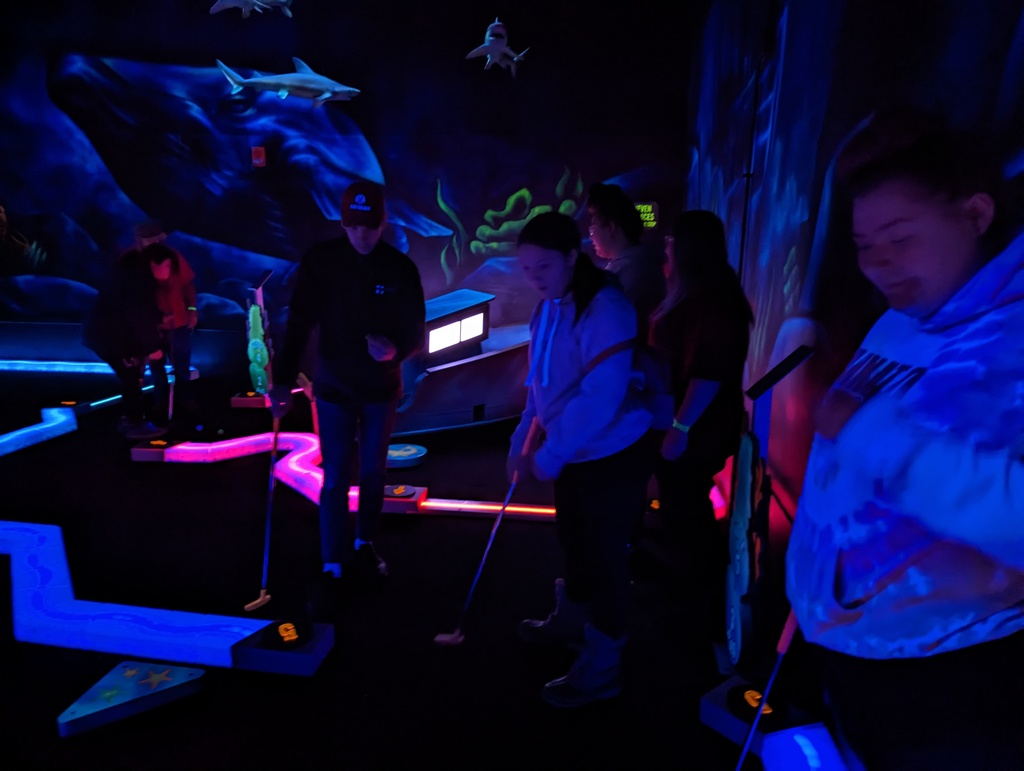 Students playing mini golf in a black light