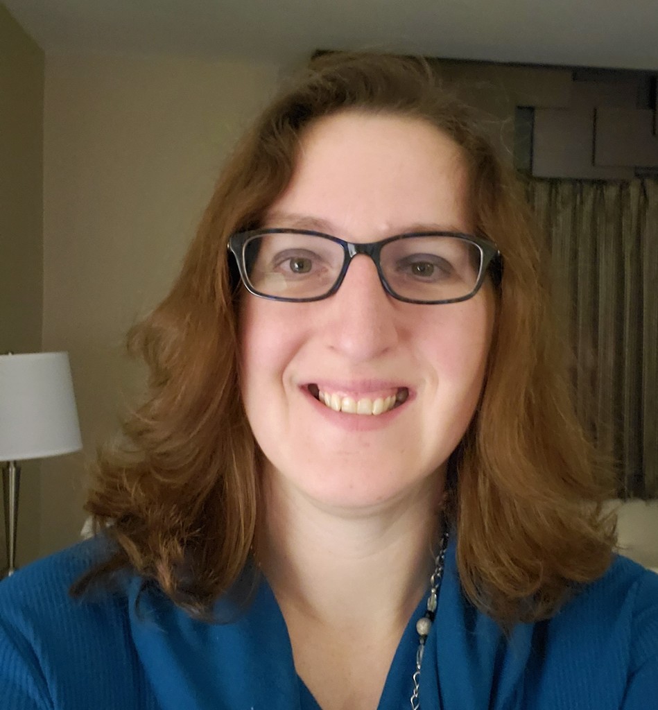 Image of Jess Balog- smiling woman with glasses and medium length hair.